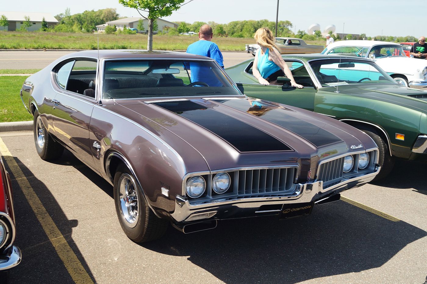 Brown 1969 Oldsmobile Cutlass W-31 with black-striped hood, front three-quarter, at a car show