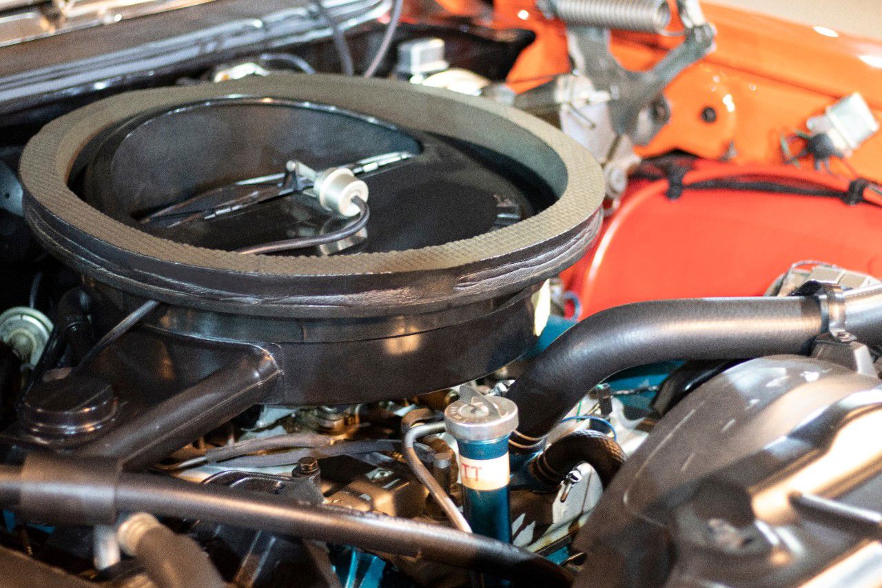 Engine bay of a 1970 Oldsmobile 4-4-2 W-30, with the fiberglass air-cleaner housing and red inner fenders
