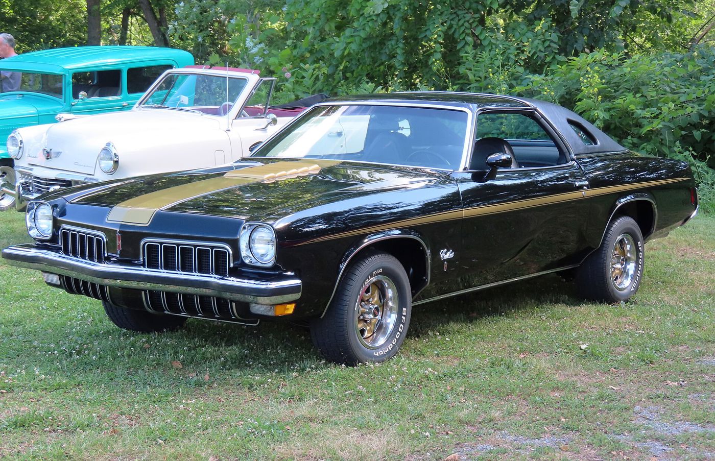 Black 1973 Hurst/Olds colonnade coupe with gold stripes, front three-quarter, on grass