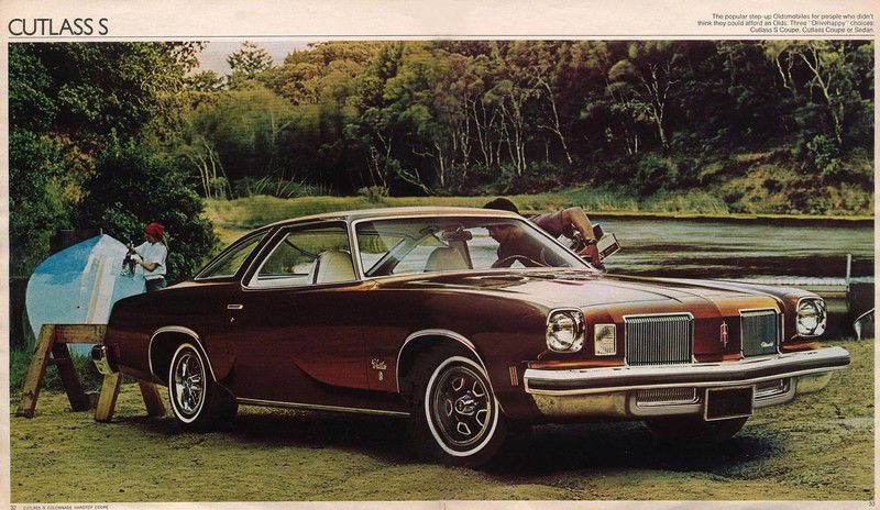 Brochure page: maroon 1974 Cutlass S coupe, front three-quarter, by a lake