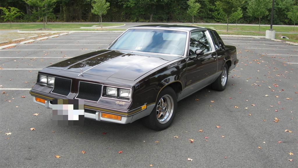 Two-tone gray 1986 Oldsmobile 4-4-2 coupe, front three-quarter, in a parking lot
