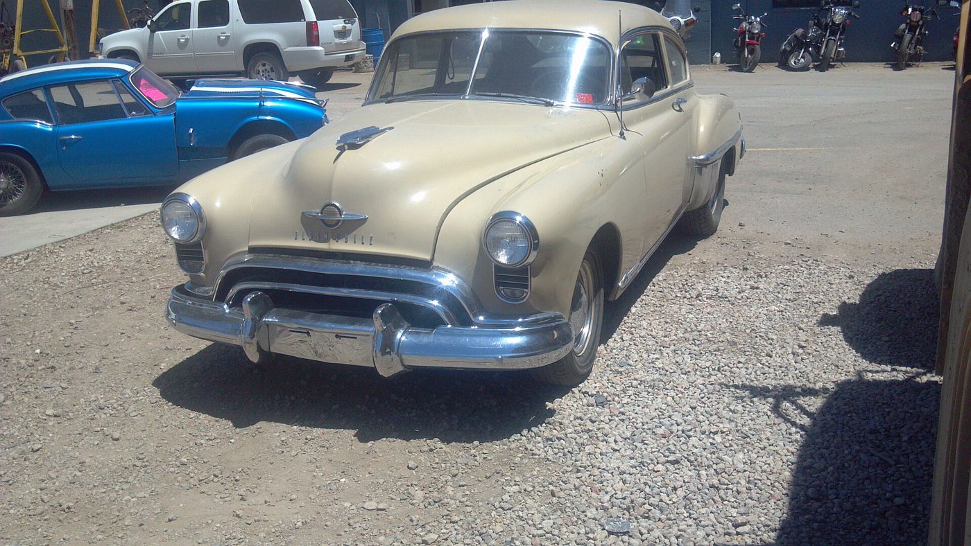 Cream 1949 Oldsmobile 88 two-door fastback, front three-quarter, on gravel