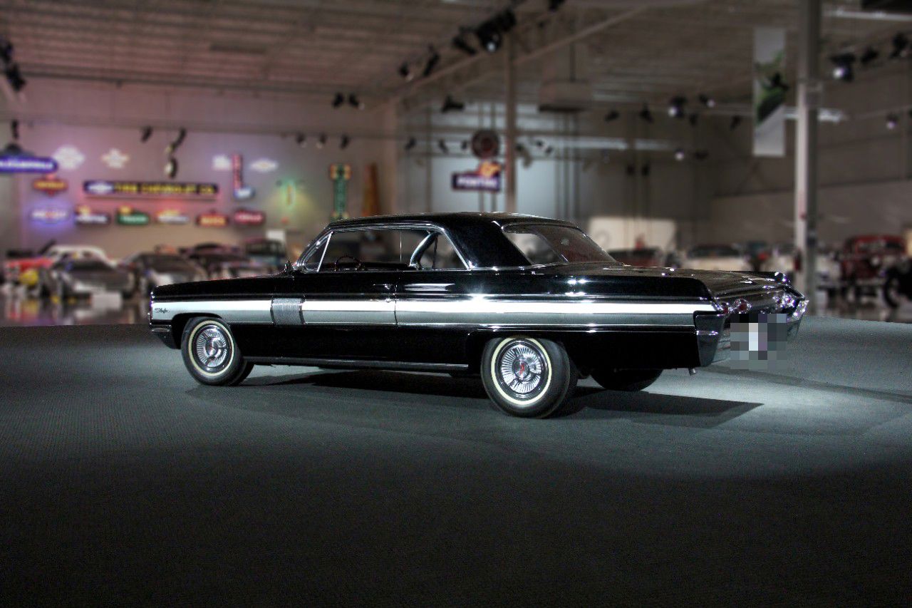 Black 1962 Starfire hardtop from the rear three-quarter, showing the side panel and taillamps