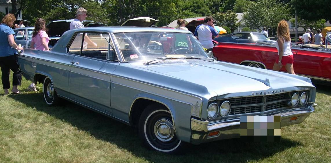 Silver-blue 1963 Oldsmobile Starfire hardtop coupe, front three-quarter, at an outdoor car show