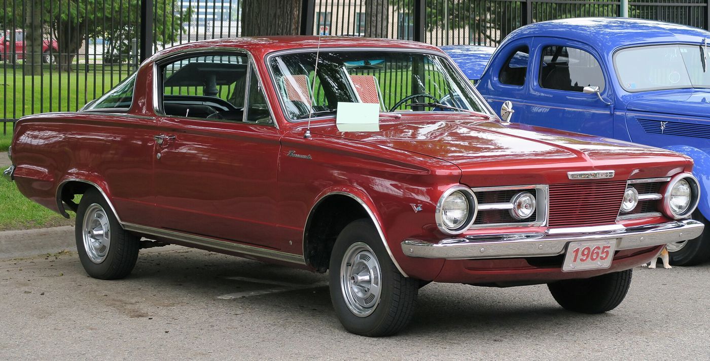 Medium red 1965 Plymouth Barracuda fastback parked at a show, front three-quarter