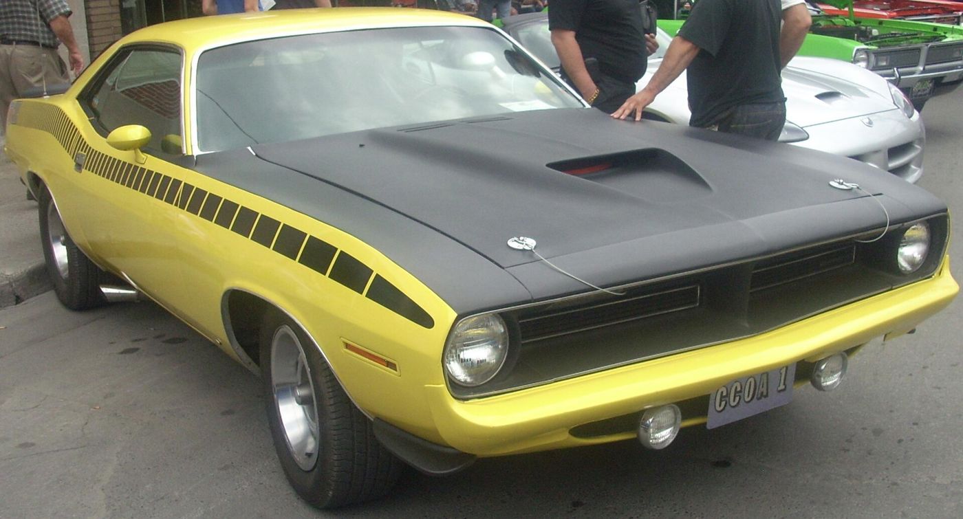 Yellow 1970 Plymouth Cuda with black hood and black side stripe, seen close at a car show