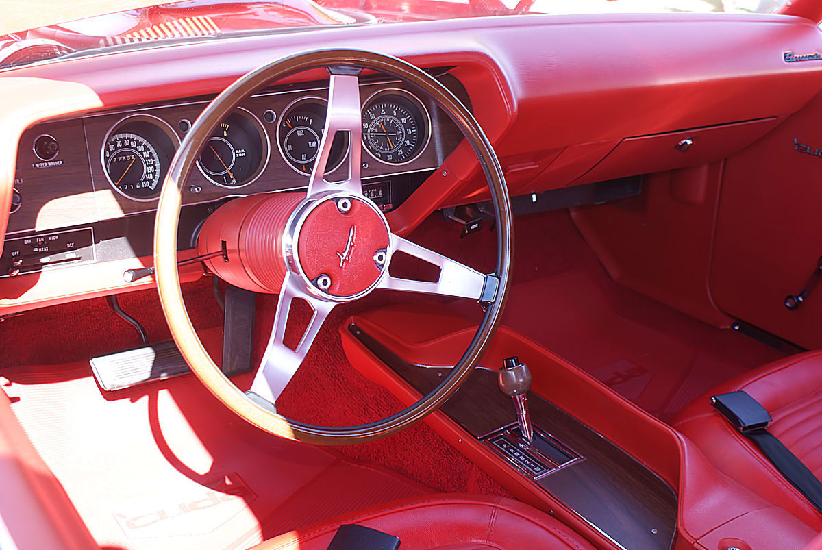 Driver's view of a 1970 Hemi Cuda: three-spoke wheel, round Rallye gauges, console shifter and red upholstery