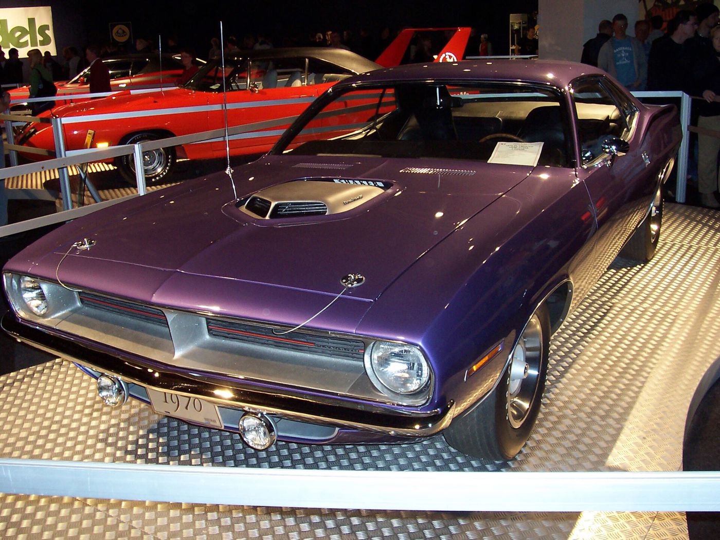 Purple 1970 Plymouth Hemi Cuda with its Shaker hood scoop and single headlamps, displayed at an indoor show