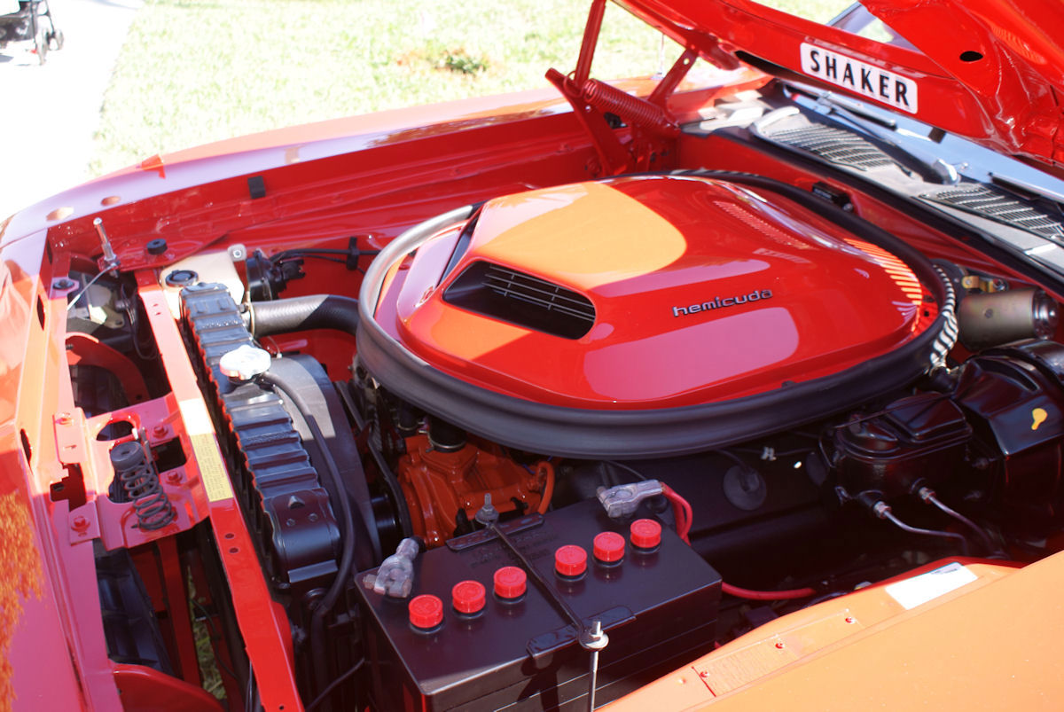 Engine bay of a red 1970 Hemi Cuda with the orange Shaker air cleaner lettered hemicuda and the underside of the hood marked SHAKER