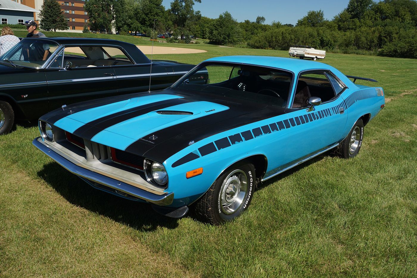 Bright blue 1973 Plymouth Cuda with black hood stripes, strobe side stripe and rear spoiler, on grass