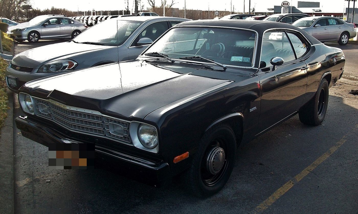 Black 1976 Plymouth Duster with a vinyl roof, front three-quarter in a car dealer lot