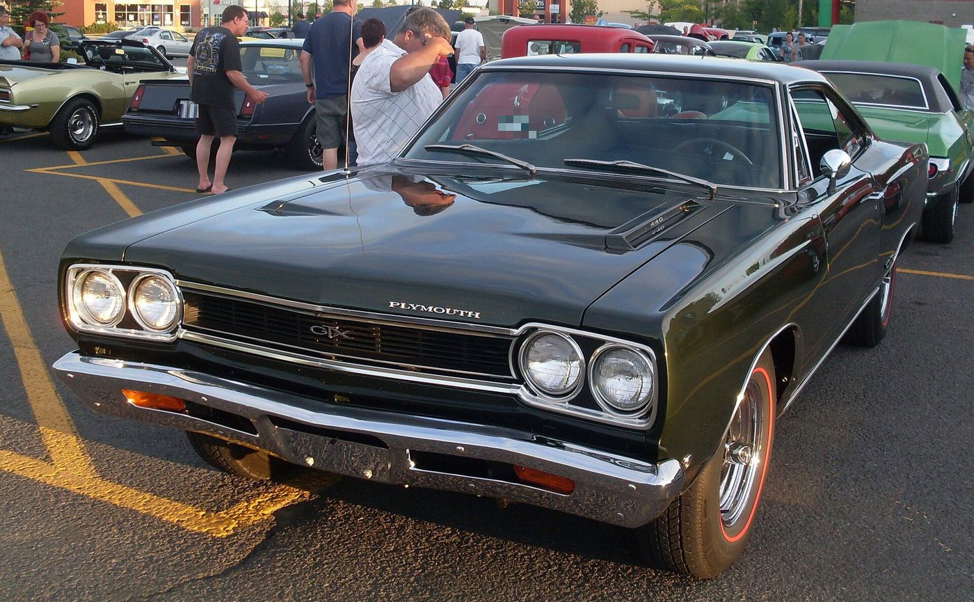Black 1968 Plymouth GTX with the GTX grille badge and quad headlamps, front three-quarter at a car show