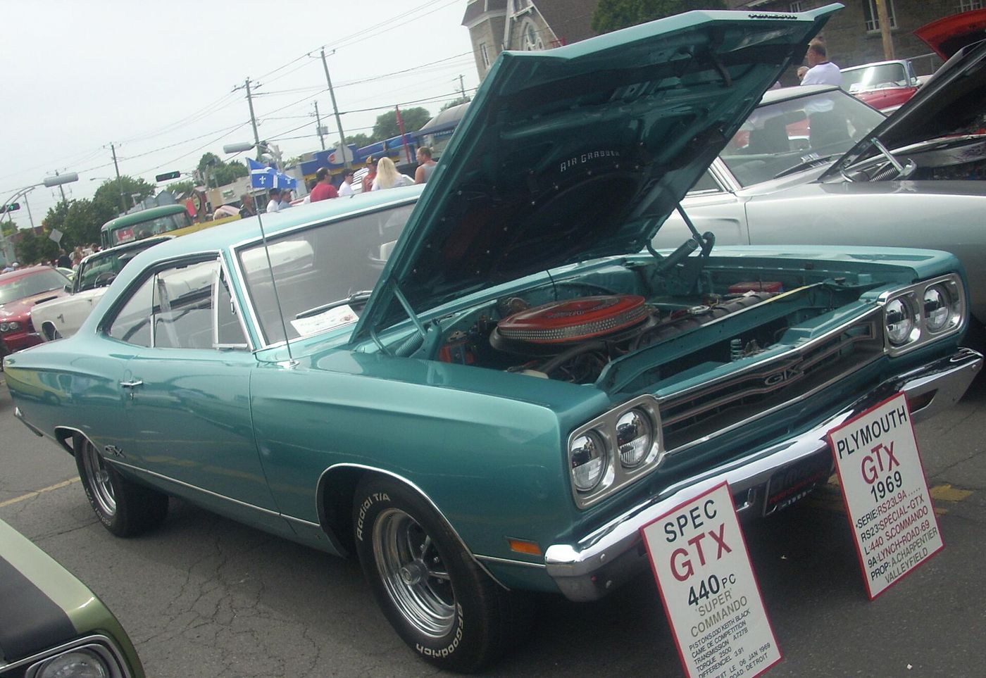Teal 1969 Plymouth GTX with the hood raised and the owner's spec board reading GTX 440 Super Commando