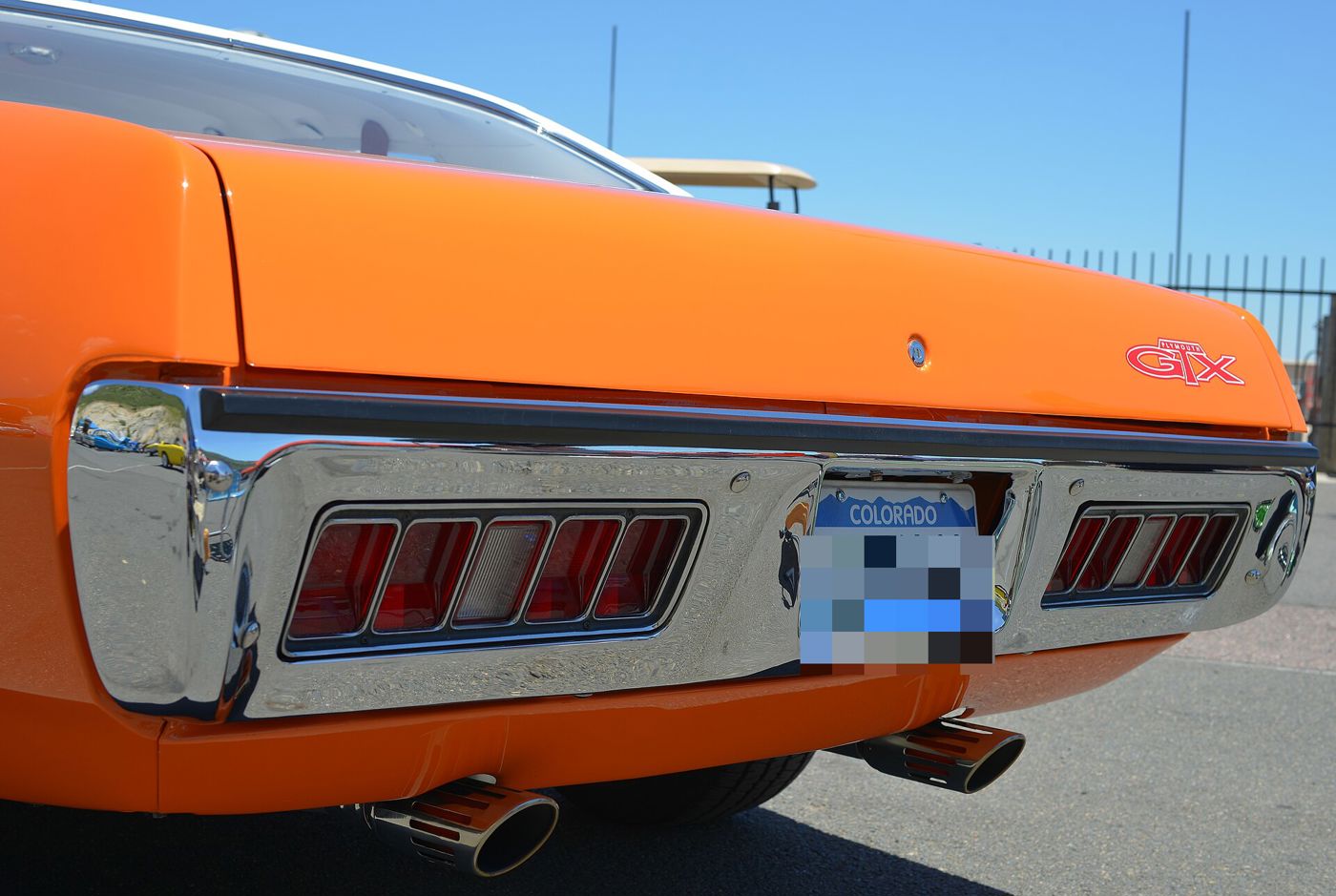 Close-up of the chrome rear bumper with inset taillamps and red GTX badge on an orange 1971 Plymouth GTX