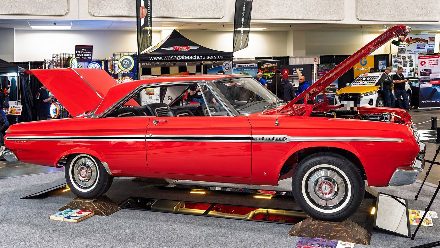 Red 1964 Plymouth Fury two-door hardtop in profile at an indoor show, hood and trunk raised