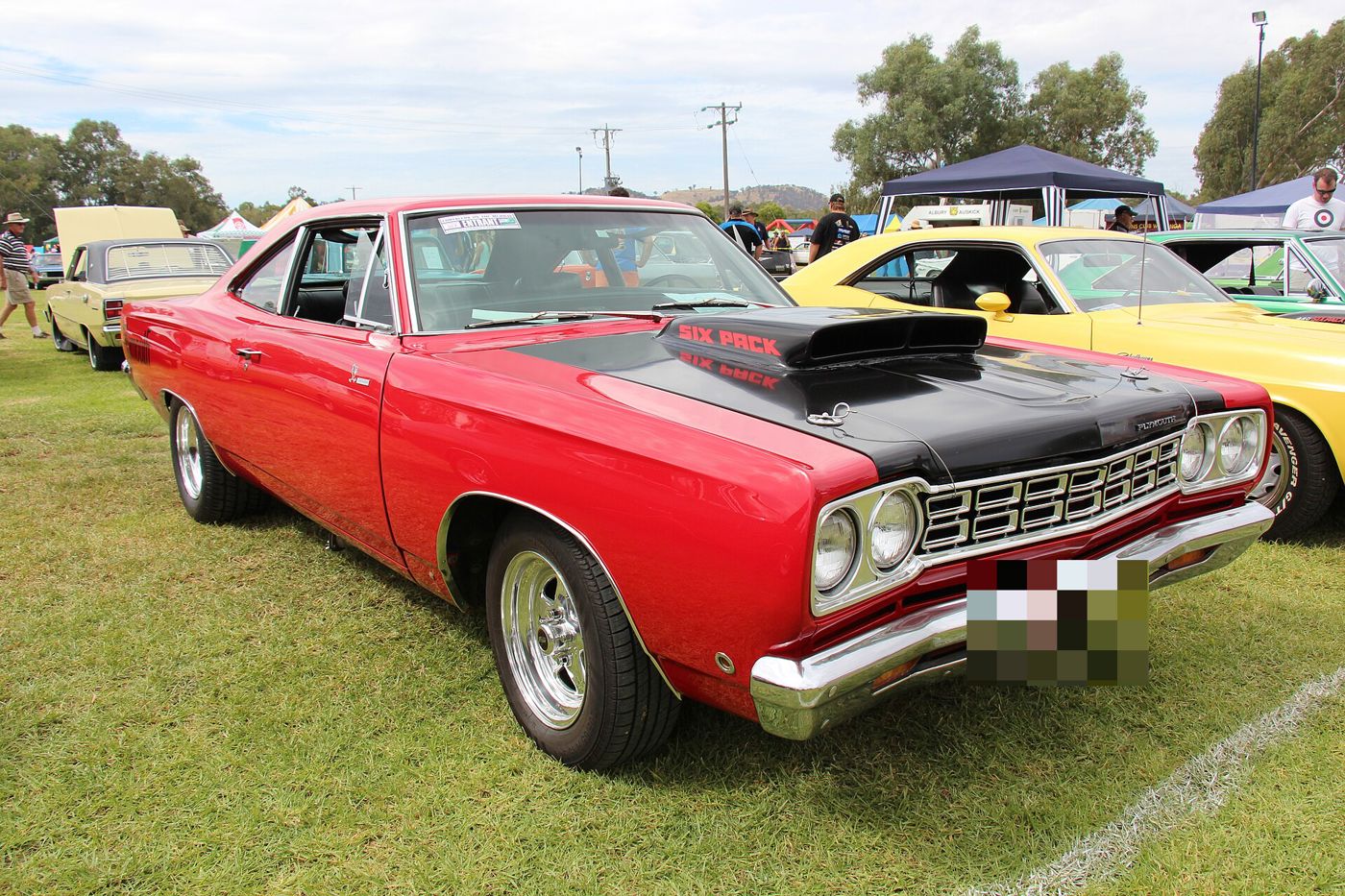 Red 1968 Plymouth Road Runner with a black fibreglass hood and large scoop marked SIX PACK, front three-quarter at a car show