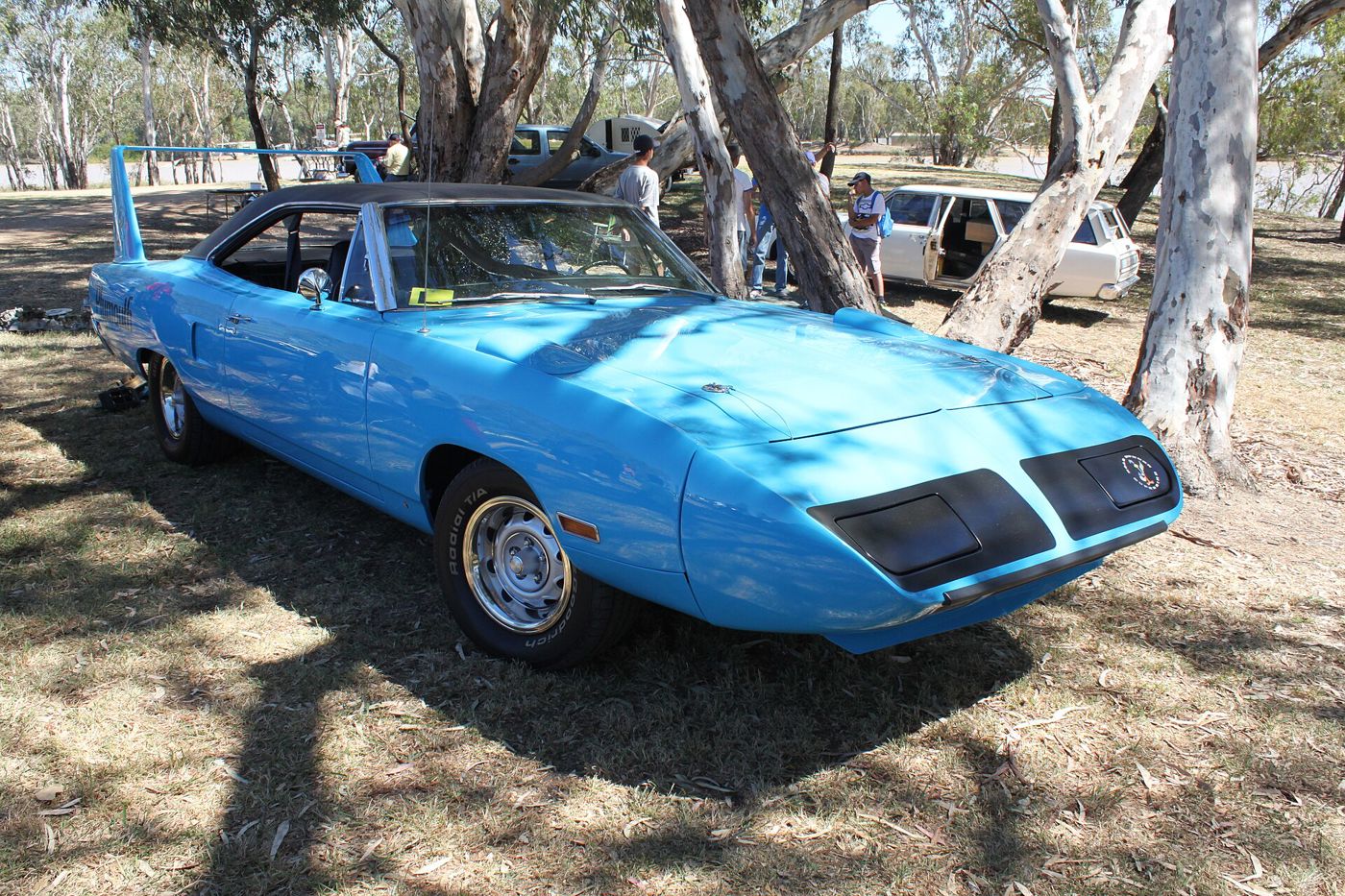 Petty Blue 1970 Plymouth Road Runner Superbird parked under trees, with the pointed nose cone, hidden headlamps and rear wing