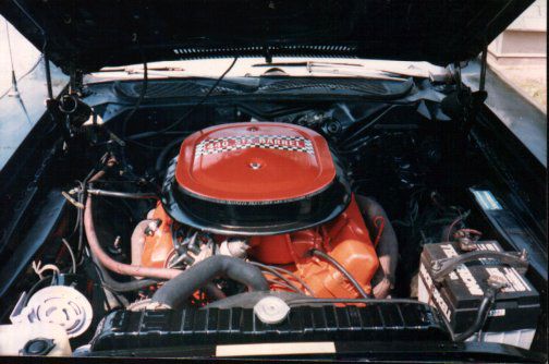 Engine bay of a 1971 Plymouth Road Runner with the orange 440 Six Barrel V8 and its large oval air cleaner