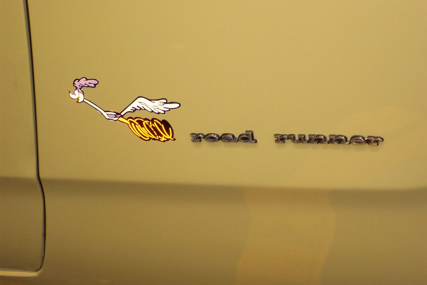 Close-up of the cartoon road runner decal and chrome road runner script on a gold 1972 Plymouth Road Runner