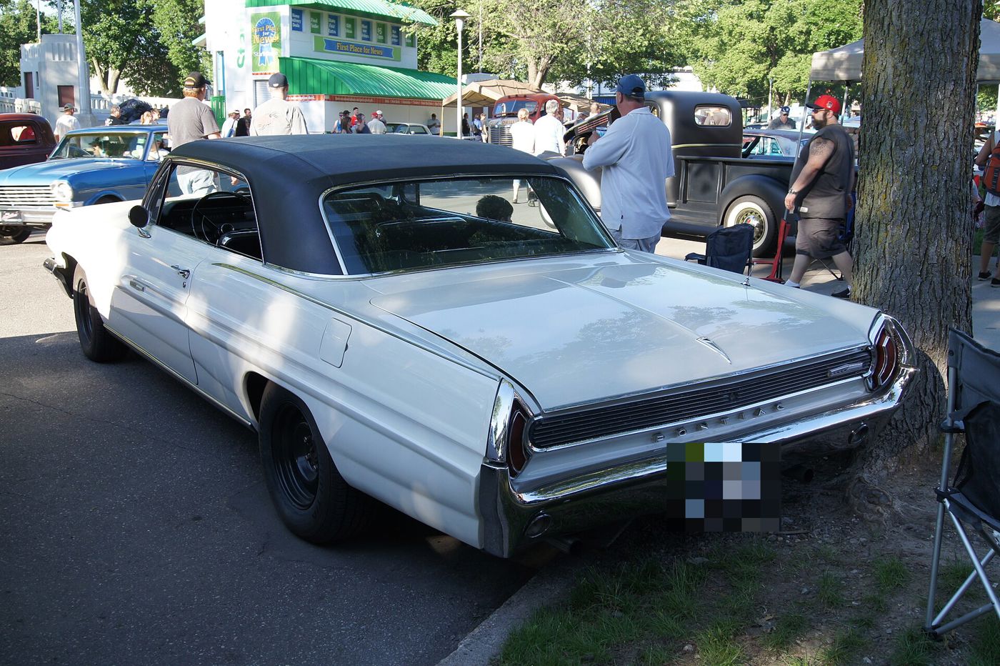 White 1962 Catalina two-door hardtop with a black roof seen from the rear three-quarter at an outdoor car show