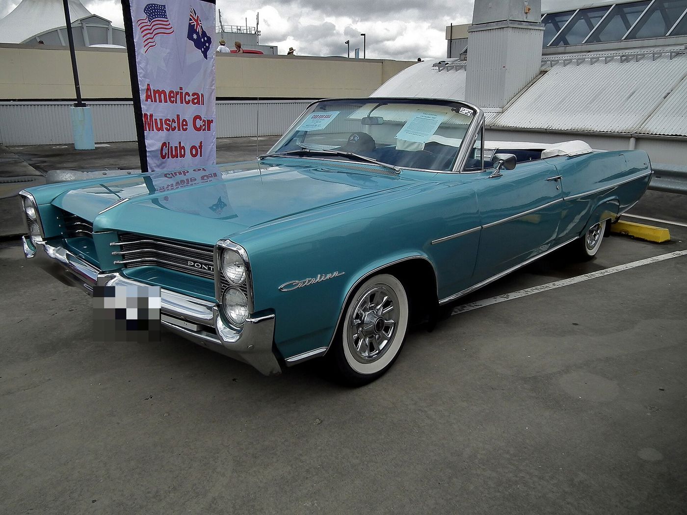Turquoise 1964 Catalina convertible with its top down, seen from the front three-quarter at a club display