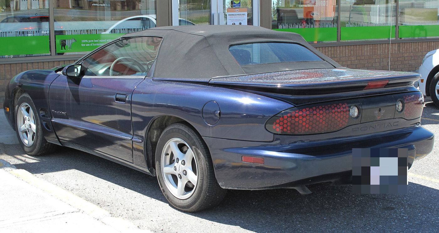 Dark blue 2000 Firebird convertible with its top up, rear three-quarter showing the honeycomb taillamps
