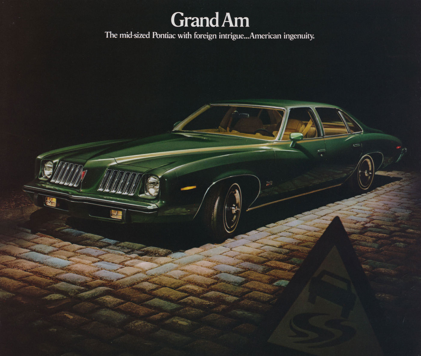 Dark green 1974 Grand Am four-door on cobblestones at night beside a road sign, under the heading Grand Am