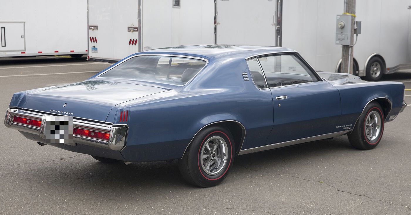 Blue 1969 Pontiac Grand Prix SJ seen from the rear three-quarter, with Grand Prix deck-lid script, Grand Prix SJ fender badge, Rally II wheels and redline tires