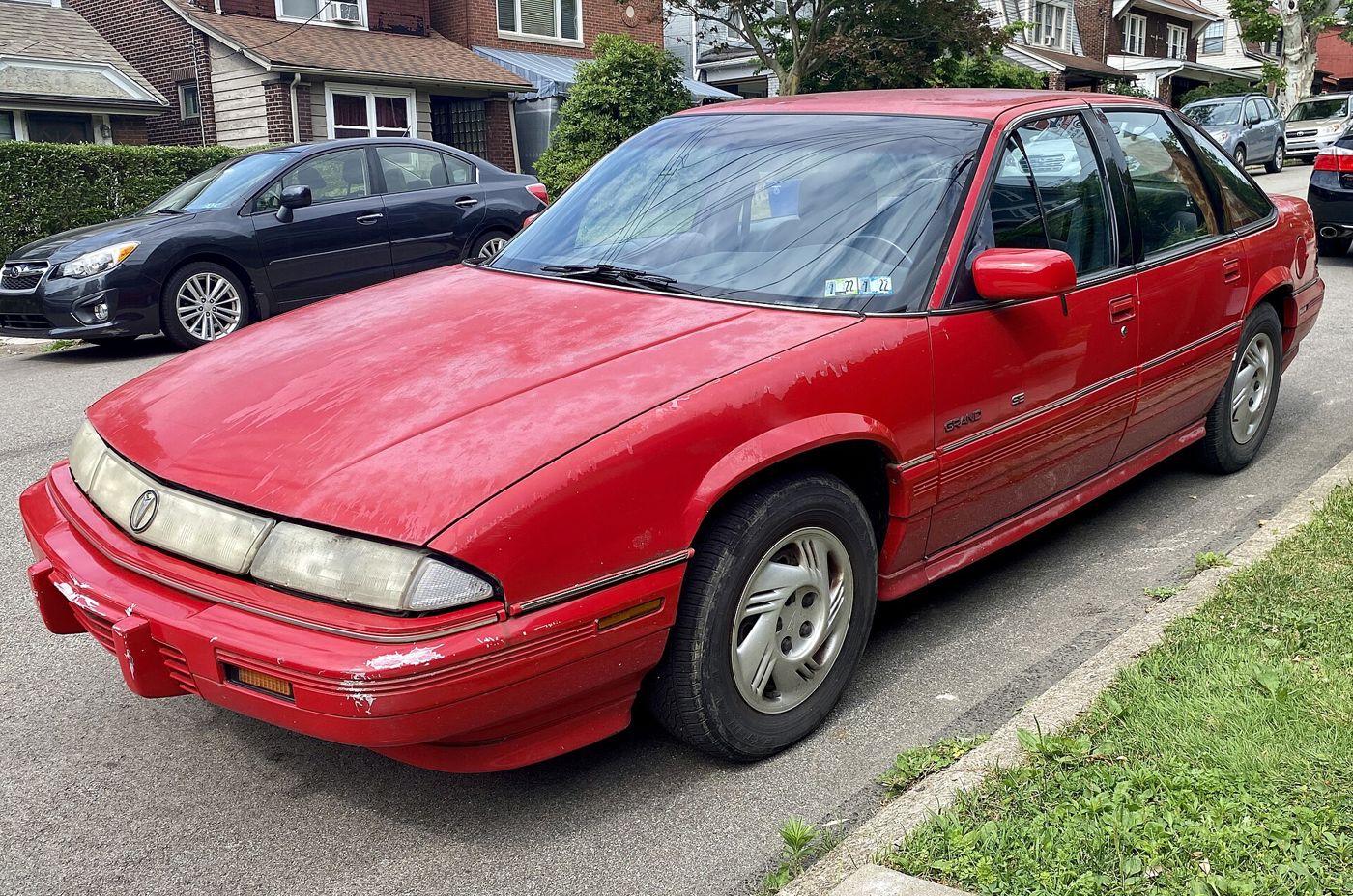 Red 1995 Grand Prix SE sedan with its wide-grille nose, front three-quarter parked on a residential street