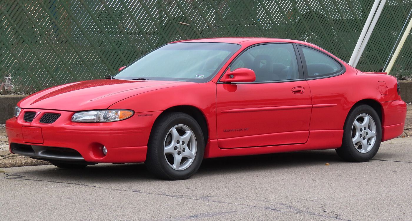 Red 1997 Grand Prix GT coupe with the wide-track stance and split twin grilles, front three-quarter on a street
