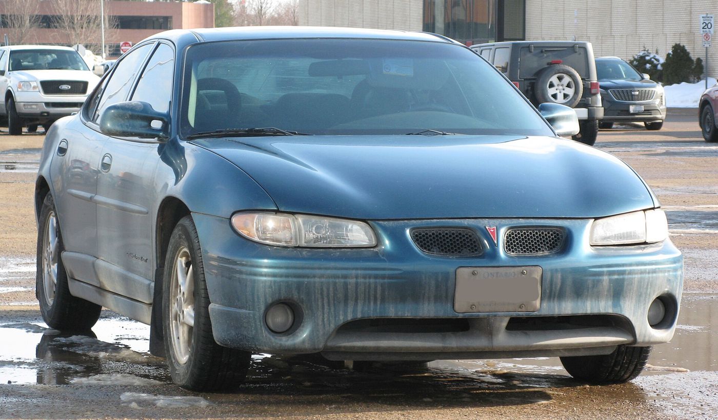Weathered blue 2003 Grand Prix GT sedan seen nearly head-on in a slushy parking lot