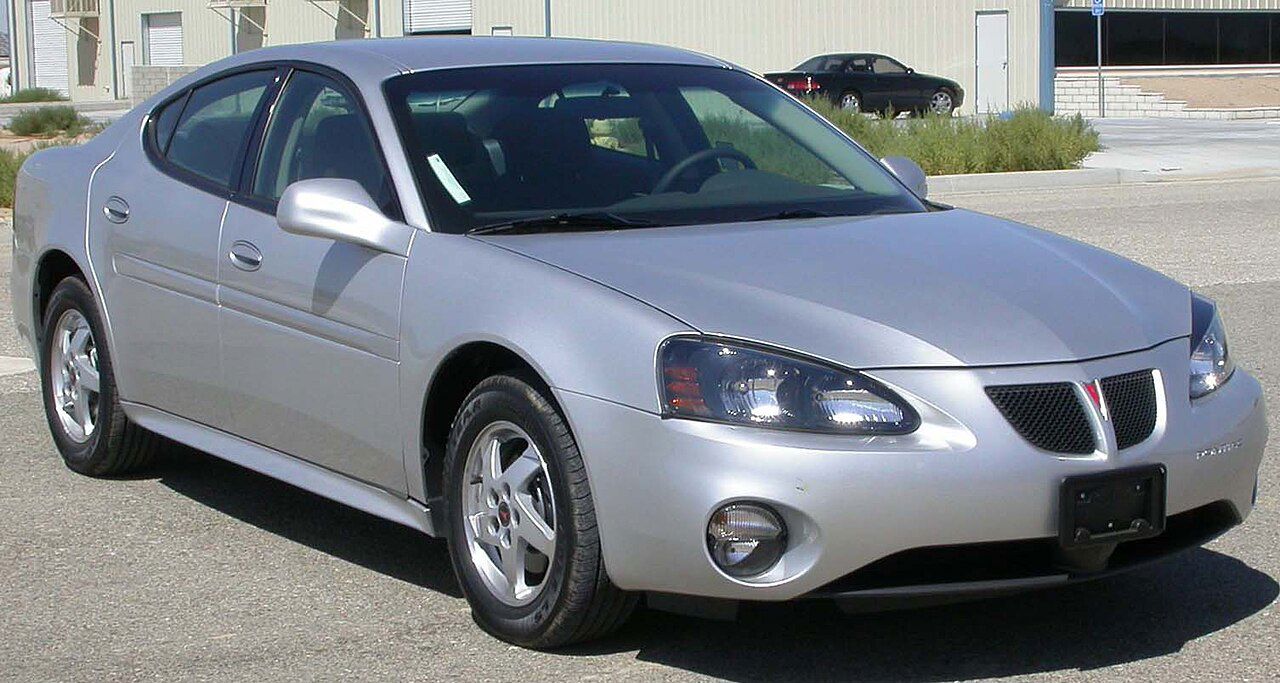 Silver 2004 Grand Prix sedan with twin mesh grilles and fog lamps, front three-quarter in a parking lot