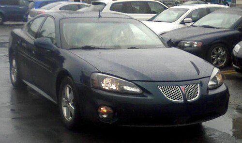 Dark blue 2005 Grand Prix sedan with chrome mesh grilles, front three-quarter in a wet parking lot