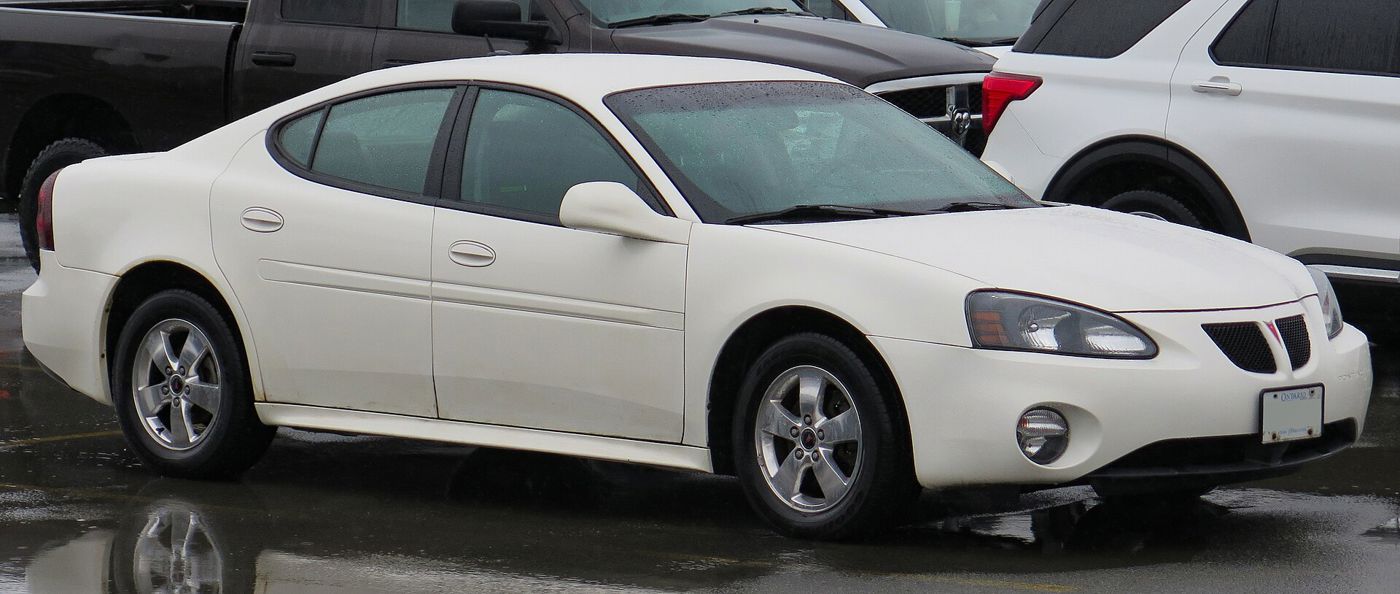 White 2006 Grand Prix sedan front three-quarter on a wet parking lot