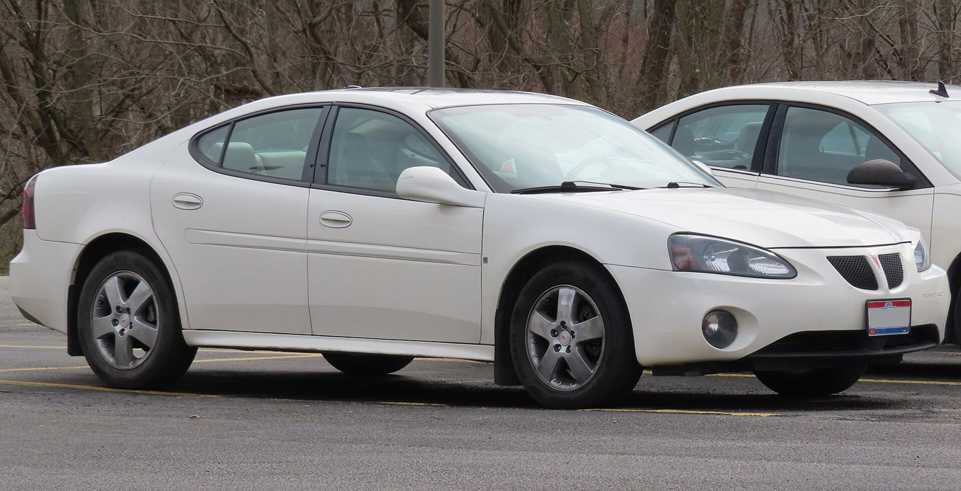 White 2007 Grand Prix GT sedan front three-quarter in a parking lot beside bare trees