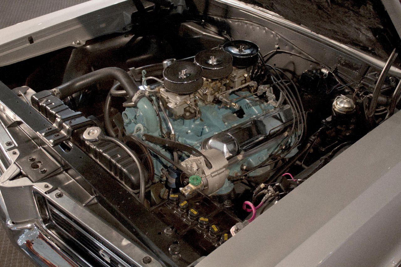 Engine bay of a 1964 GTO: a blue Pontiac 389 V-8 topped by three chrome air cleaners on the Tri-Power carburetors