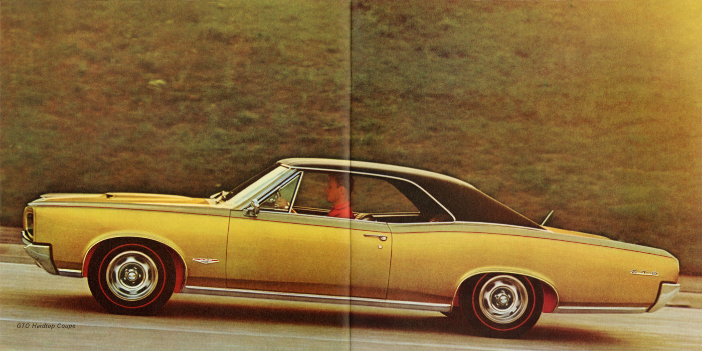 Gold 1966 GTO hardtop with a black roof in full side view on a grassy roadside, showing its kicked-up rear fender line