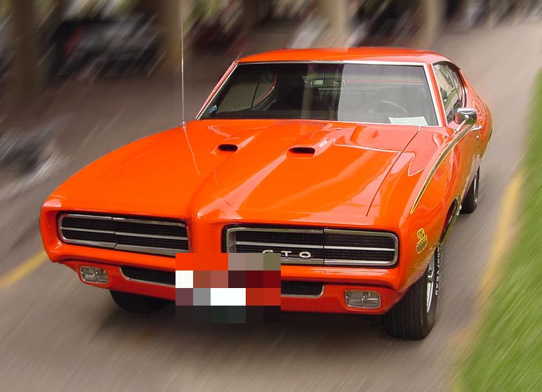 Orange-red 1969 GTO Judge hardtop with blacked-out grilles, Ram Air hood scoops, Judge decal and rear spoiler, front three-quarter