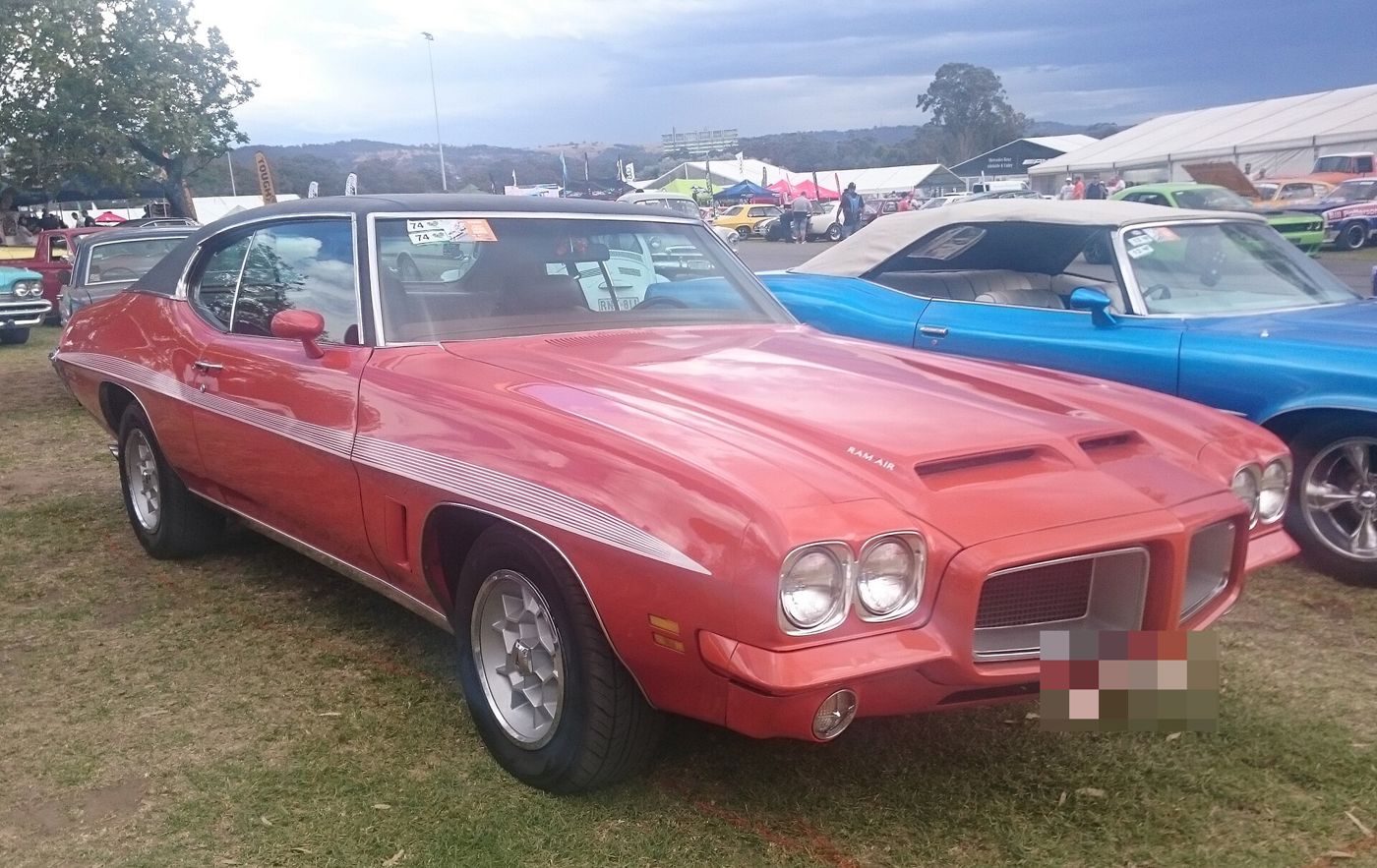 Red 1972 GTO hardtop with Ram Air hood, side stripes and front-fender air extractors, front three-quarter at an Australian car show