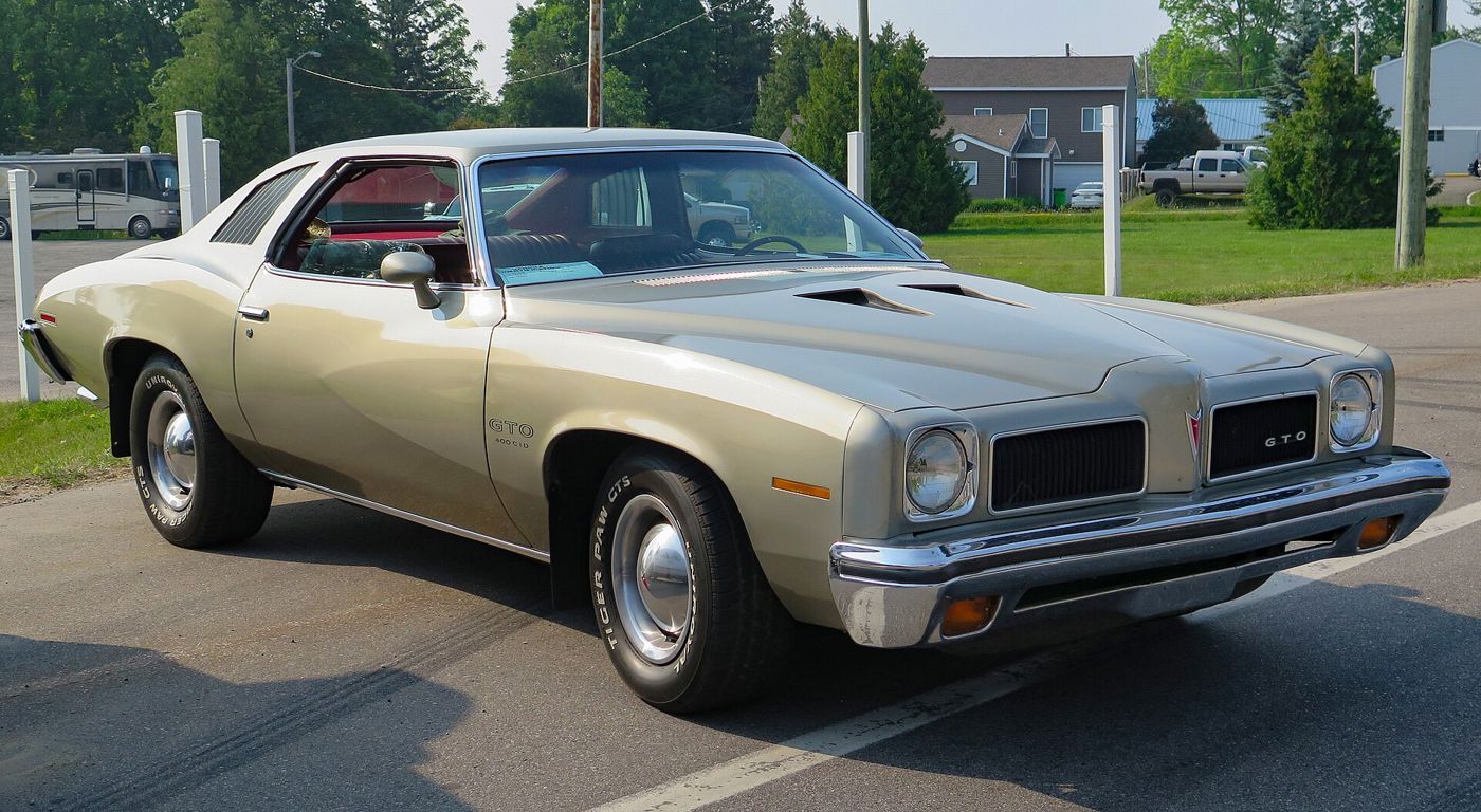 Silver 1973 LeMans Colonnade coupe with the GTO package, twin NACA hood scoops and GTO grille badge, front three-quarter in a parking lot