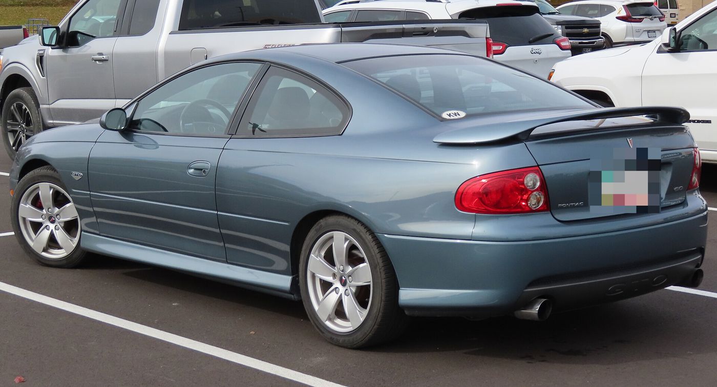 Blue-gray 2005 GTO coupe from the rear three-quarter, showing its decklid spoiler and red taillamps