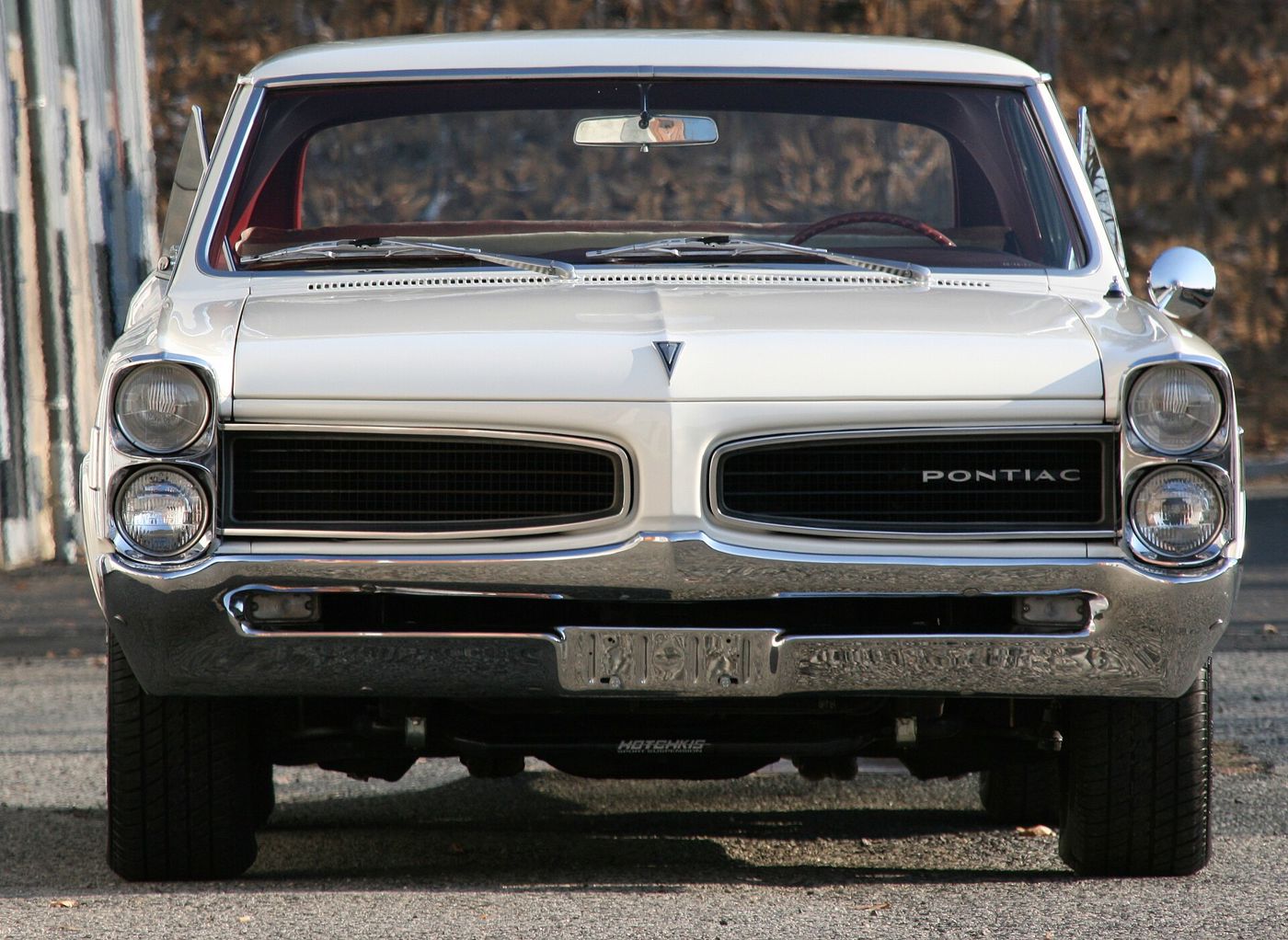 White 1966 Tempest LeMans hardtop seen head-on, with stacked headlights and a split black grille lettered PONTIAC