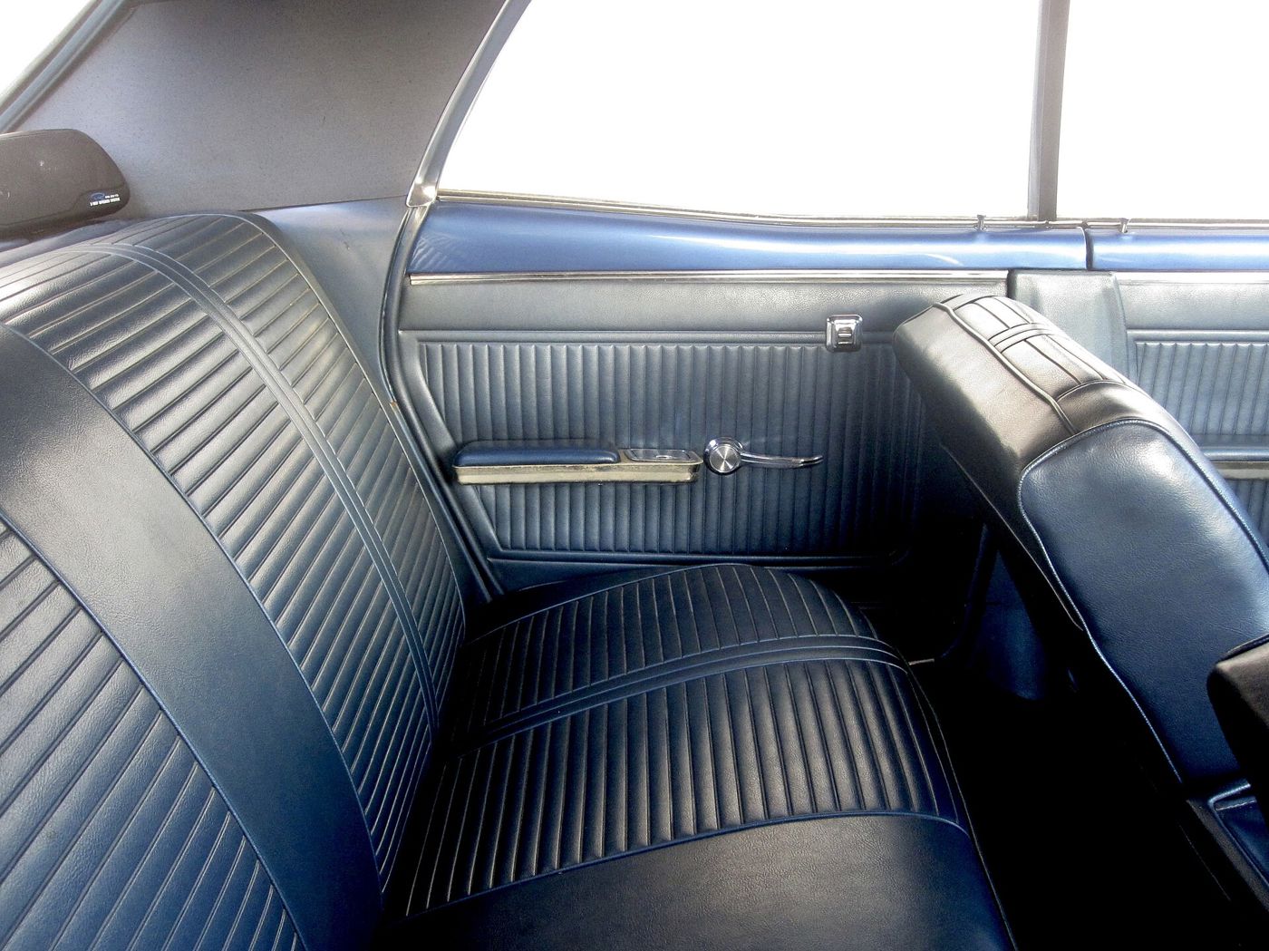 Blue vinyl bucket seats and door panel of a 1966 Pontiac LeMans seen through the open door
