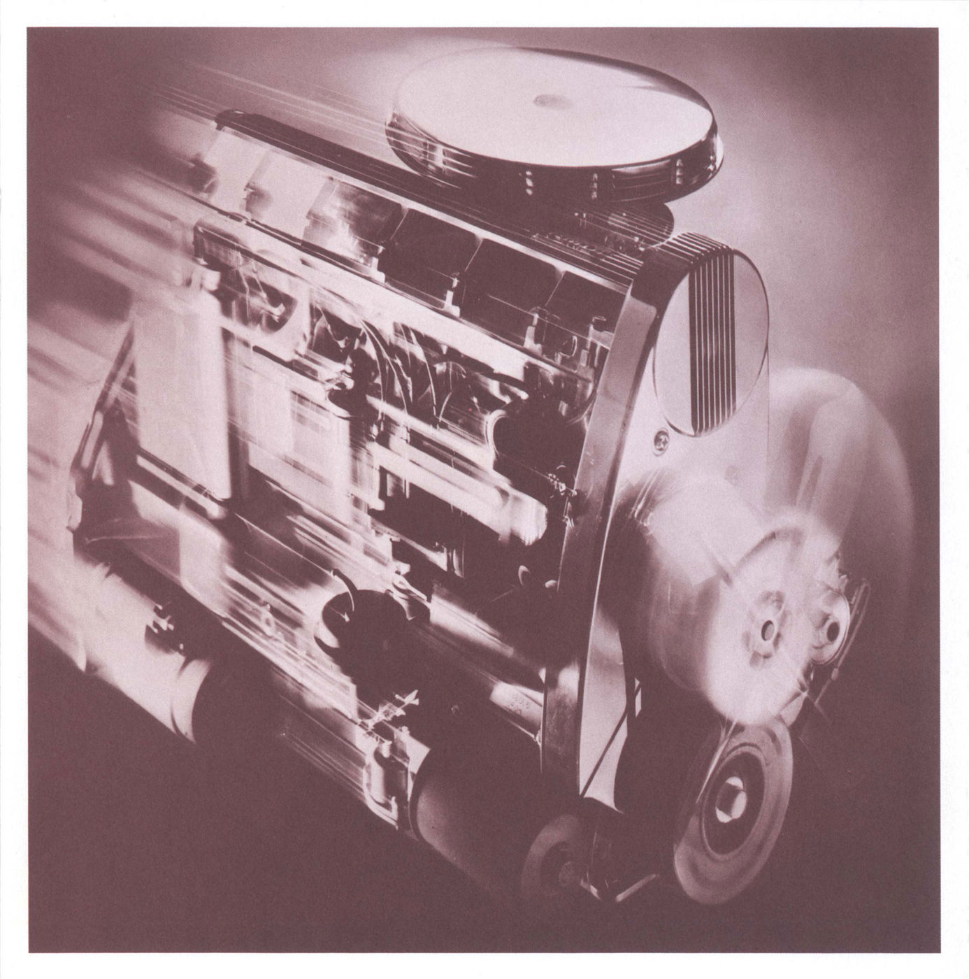 Tinted studio photo of the Pontiac overhead-cam six-cylinder engine with its cam cover and air cleaner, motion-blurred pulleys in front