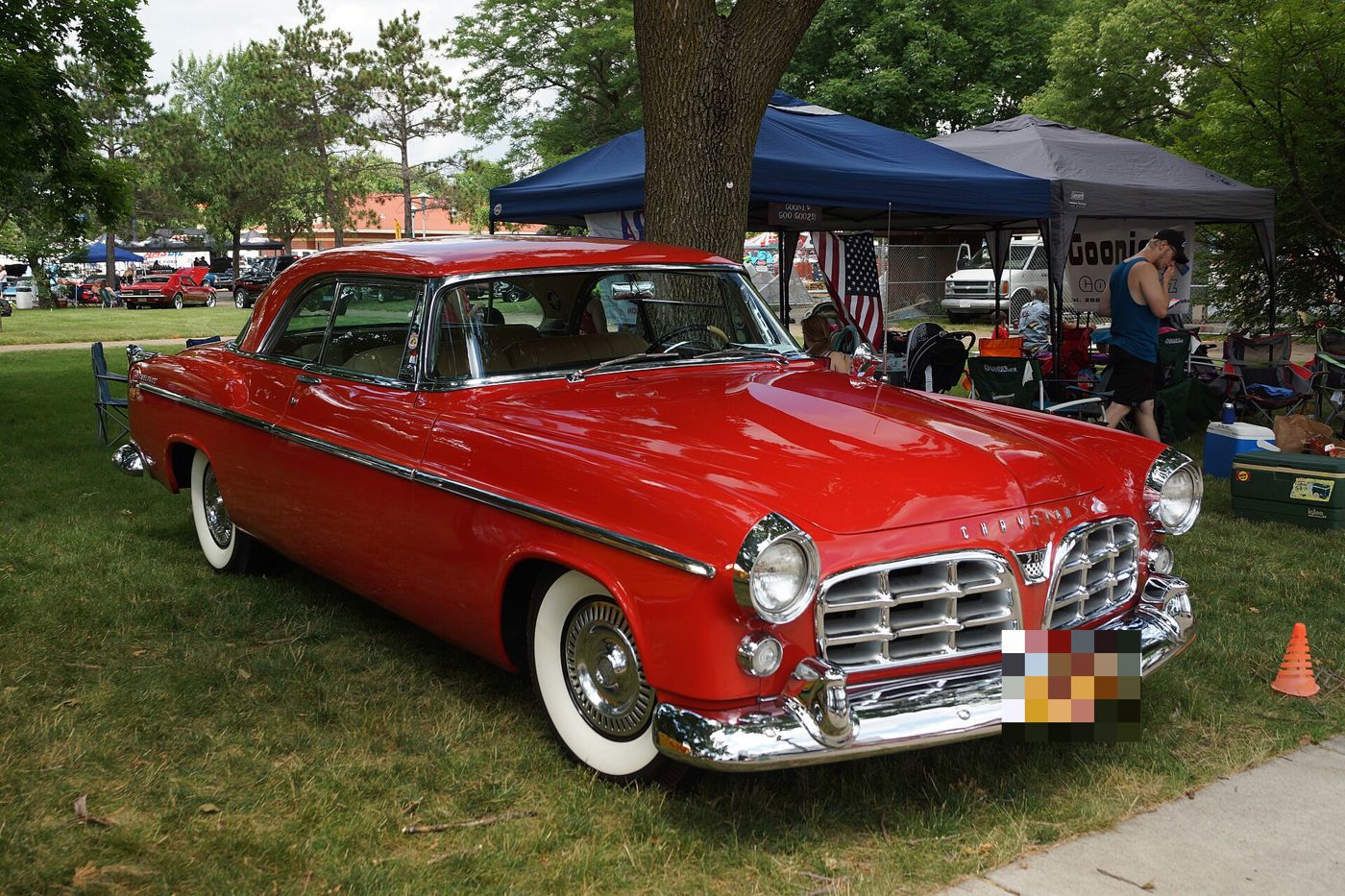 Red 1955 Chrysler C-300 hardtop with whitewall tires and the split egg-crate grille, front three-quarter at an outdoor show