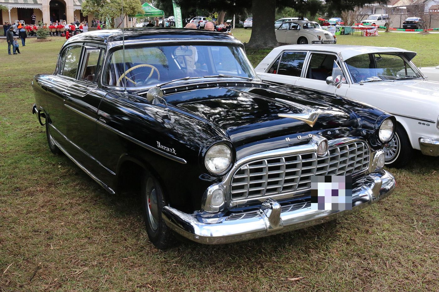 Black 1955 Hudson Hornet sedan with its wide chrome grille, front three-quarter on grass
