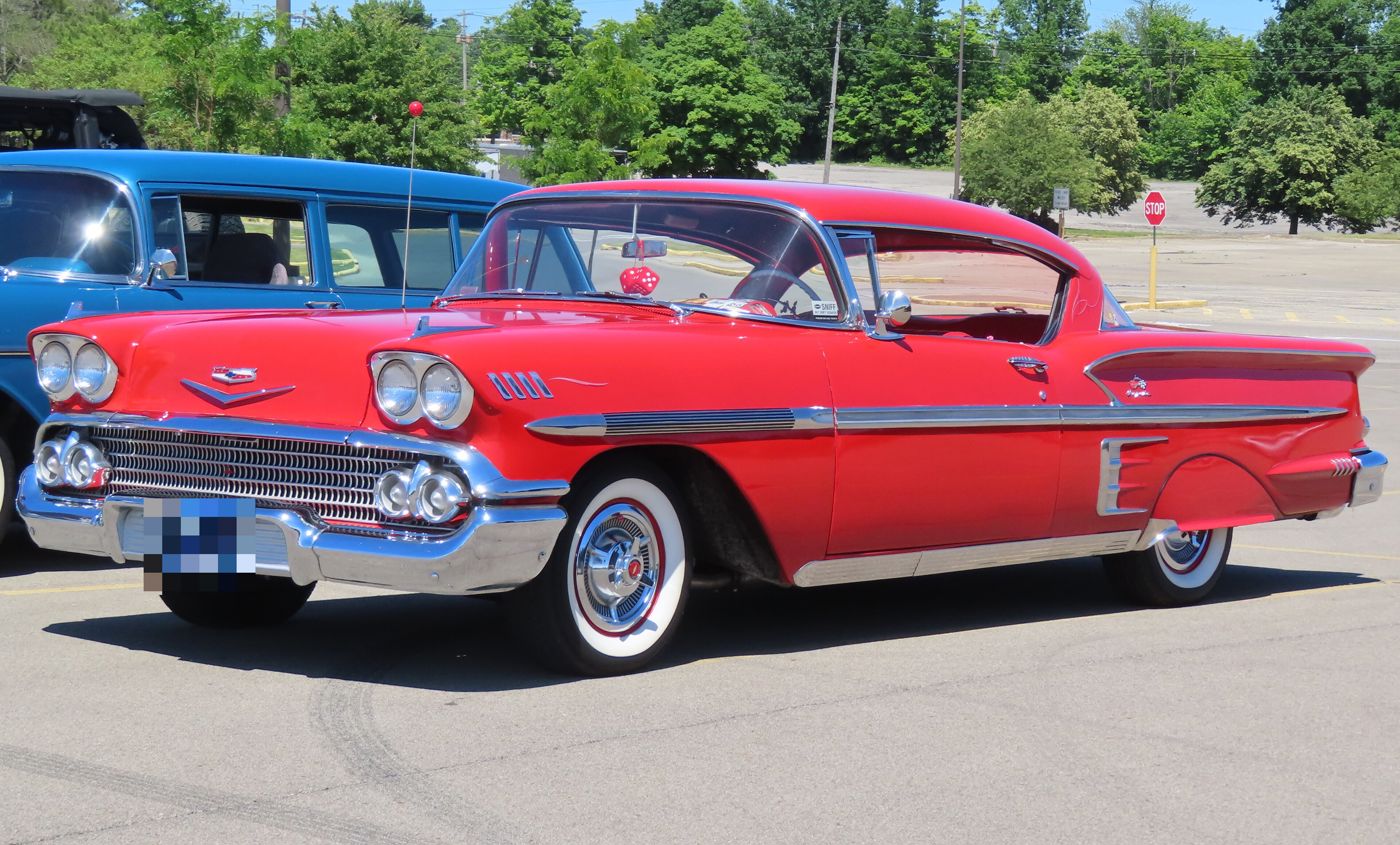 Red 1958 Chevrolet Bel Air Impala two-door hardtop in front three-quarter view, with quad headlamps, whitewall tires and a 1958 Ohio plate