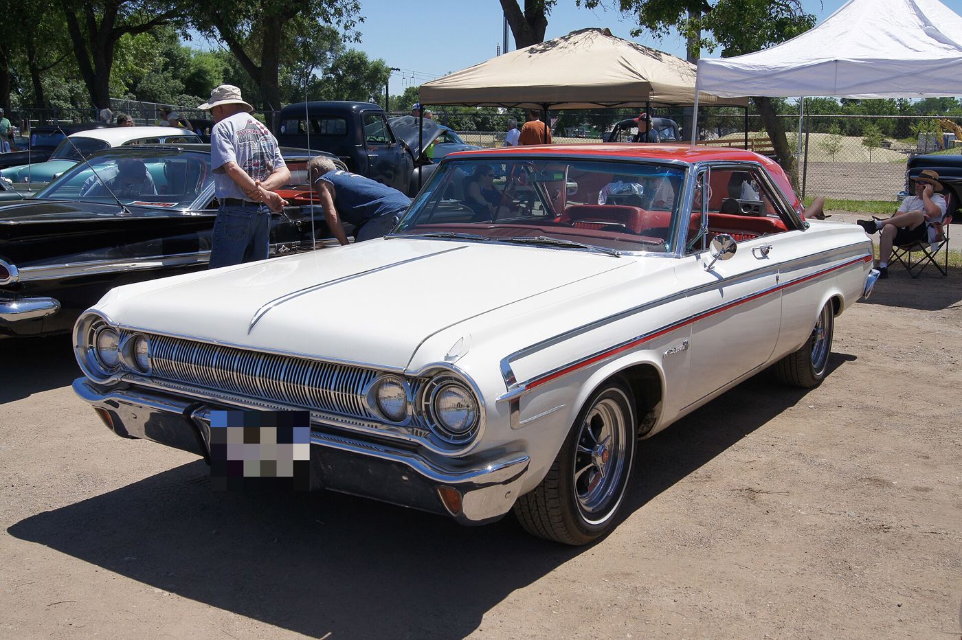 White 1964 Dodge Polara 500 hardtop with a red side spear and red interior, front three-quarter at a show
