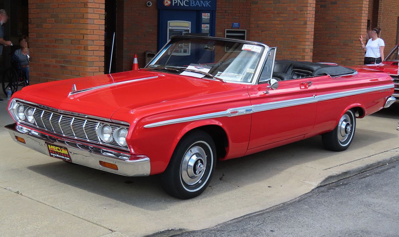 Red 1964 Plymouth Sport Fury convertible with the top down, front three-quarter on a town street