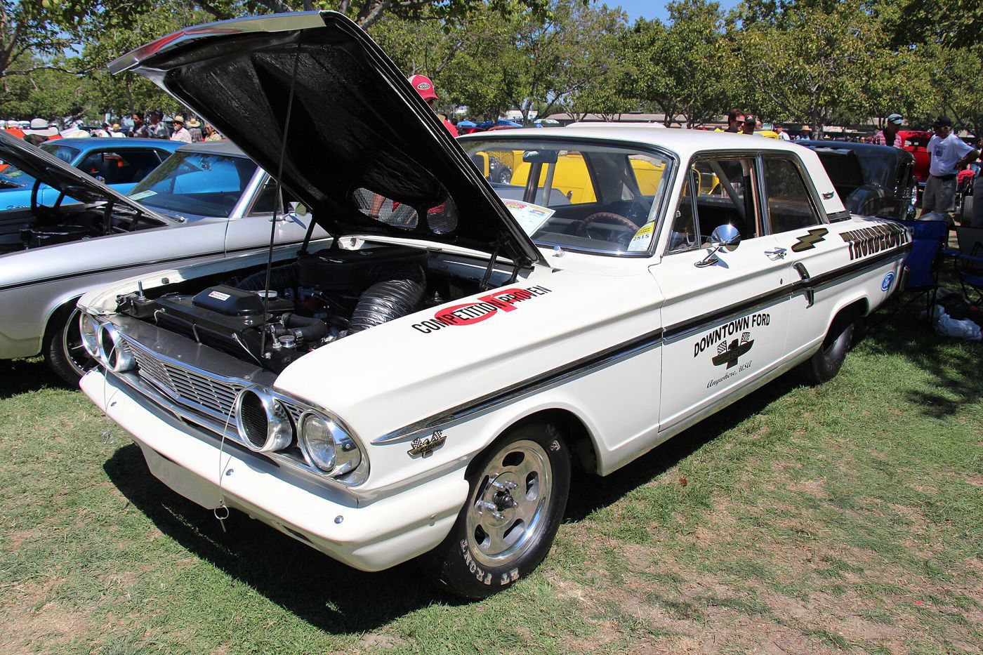 White 1964 Ford Fairlane Thunderbolt with its hood open over the 427 and Downtown Ford lettering on the doors